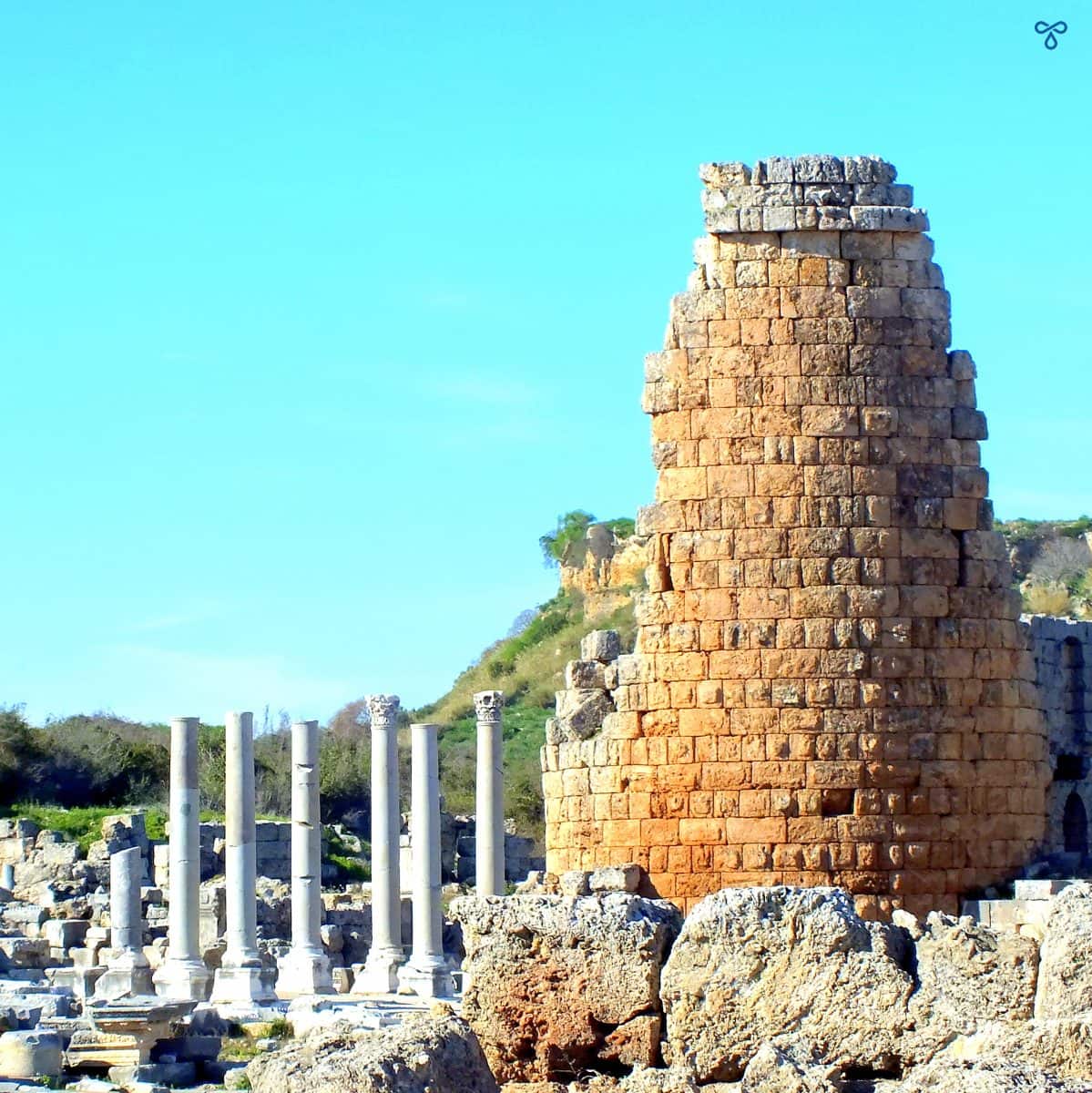 An ancient stone tower and marble columns at Perge ancient ruins.