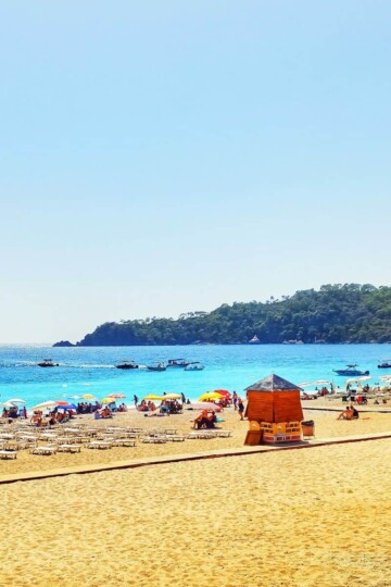 A beach with sun loungers and changing cabin