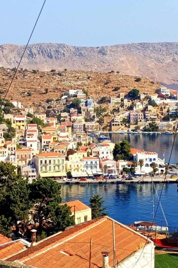A view of Symi harbour from above. Terracotta rooftops are in the foreground.