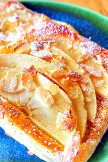 Two apple tart squares topped with sliced apples and caster sugar.