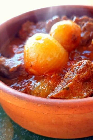 Beef and pearl onion stew in a clay pot.