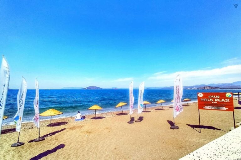 Çalış Beach public area. Flags advertise the free parasols lining the shoreline.
