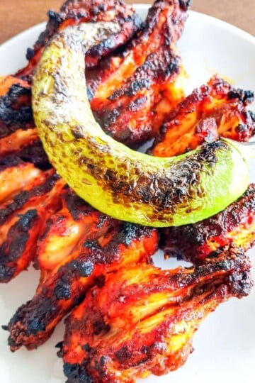 Eight barbecued chicken drumettes topped with a charred long green pepper.