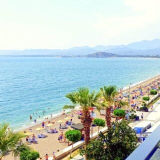 A view along the stretch of Çalış Beach from high up on Roof Bar. Sun loungers and parasols are along the beach.
