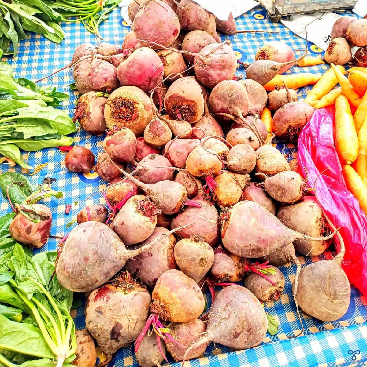 Fresh red beets of various sizes for sale on a market stall.