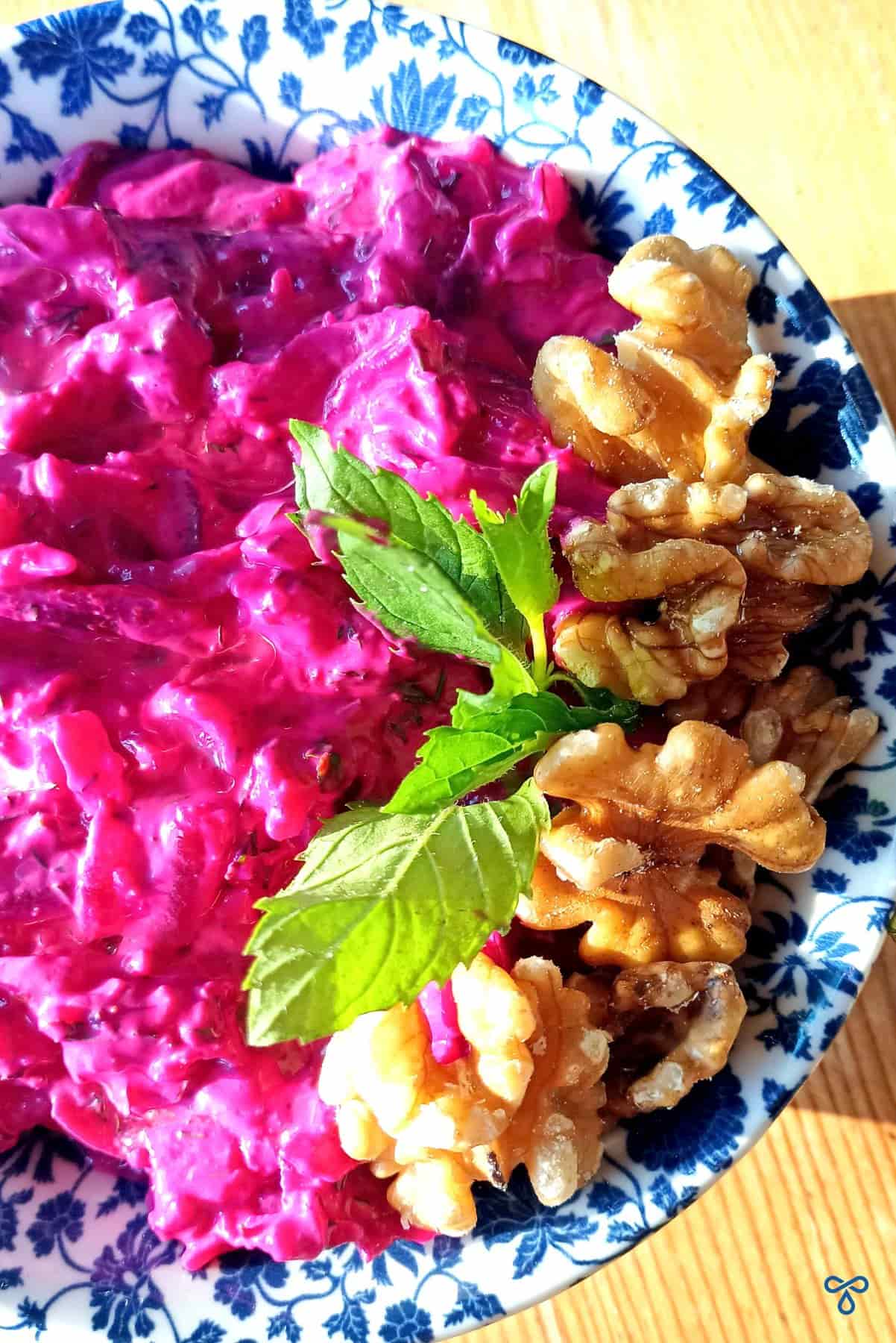 Beetroot and yoghurt dip with a garnish of walnuts and mint leaves on the side.