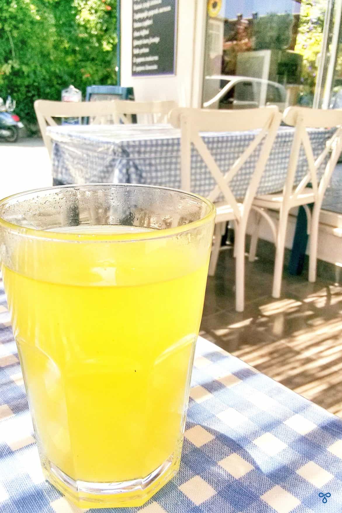 A glass of lemonade on a cafe table with a blue and white checked tablecloth.