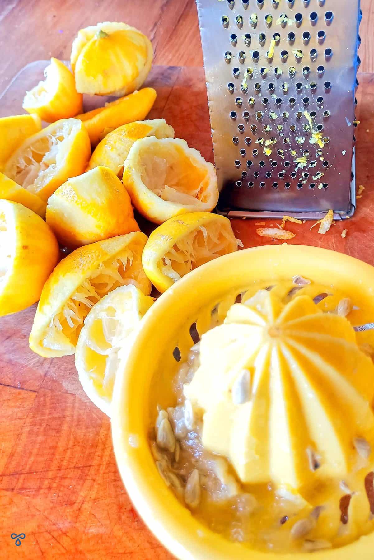 Juiced lemons, a yellow juicer and a metal grater.