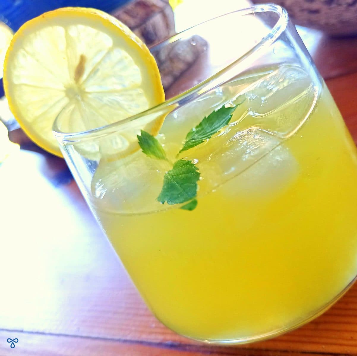A glass of Turkish lemonade with ice and fresh mint. A slice of lemon is on the edge of the glass.