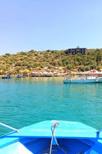 The front end of a small blue wooden boat approaching Limanağzı Bay on calm sea in Kaş