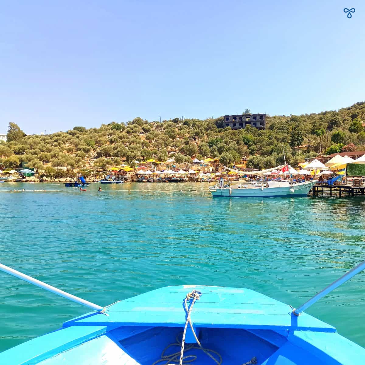 The front end of a small blue wooden boat approaching Limanağzı Bay on calm sea in Kaş.
