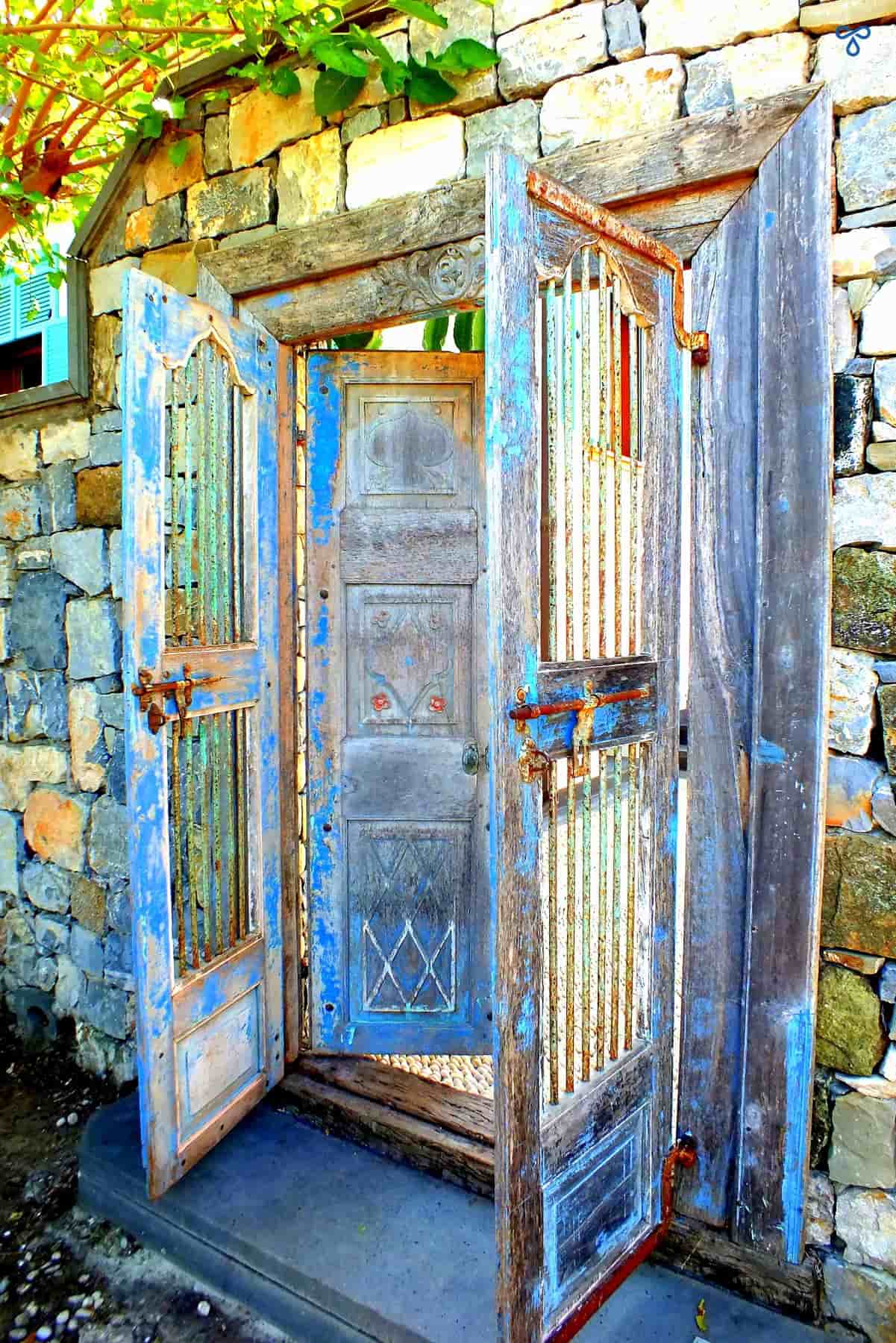 A reclaimed wooden double doorway. Old grey wood with flecks of blıue paint.