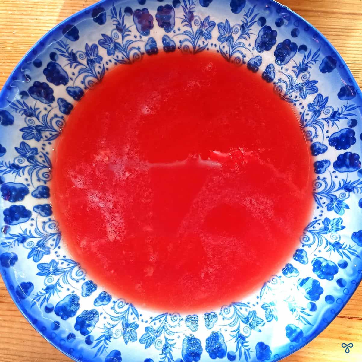 Strained tomato juice in a blue and white patterned bowl.