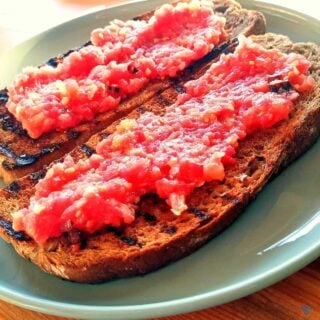 Two slices of griddled brown bread topped with tomato pulp to make Spanish tomato bread.