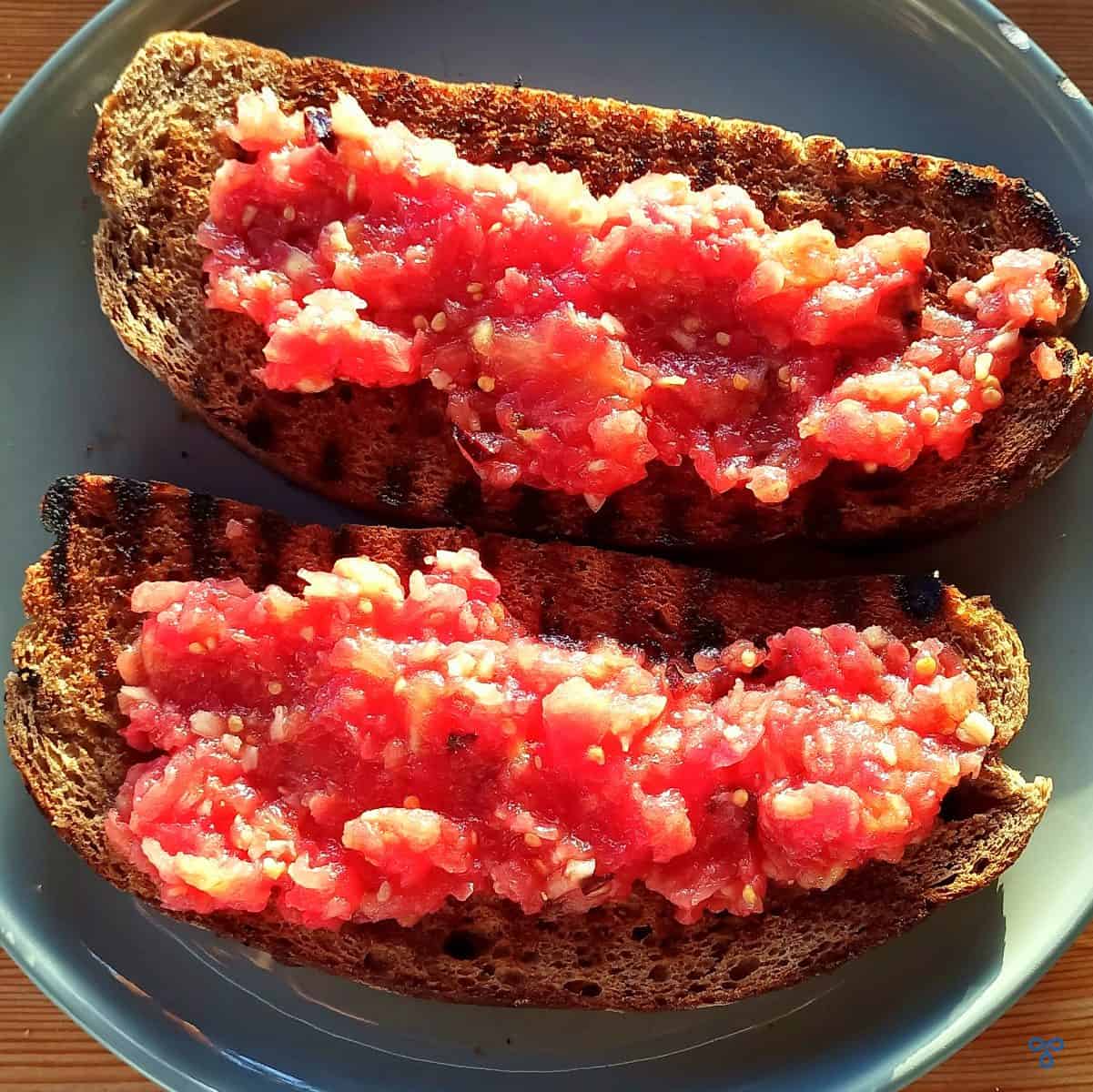 Two slices for toasted bread topped with tomato pulp - pan con tomate.