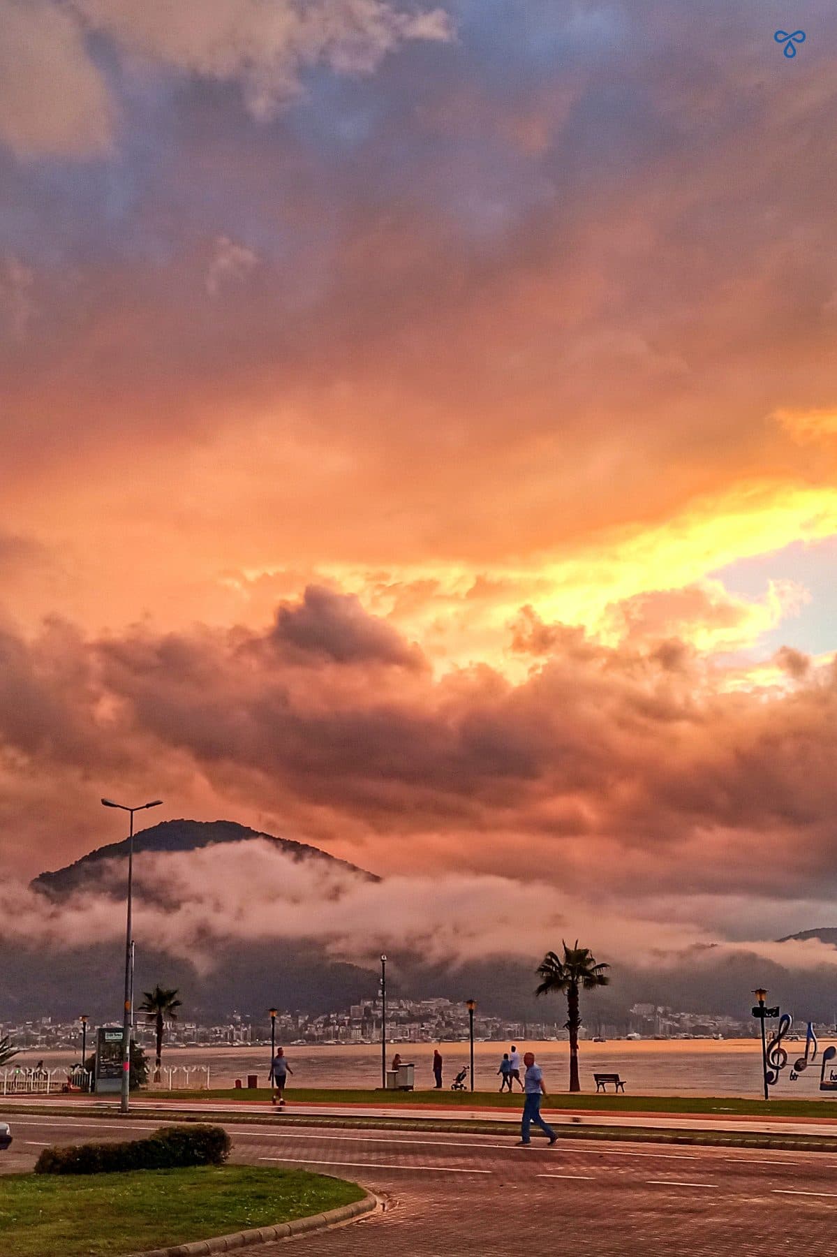 A cloudy sunset over the sea with a main road in the foreground.