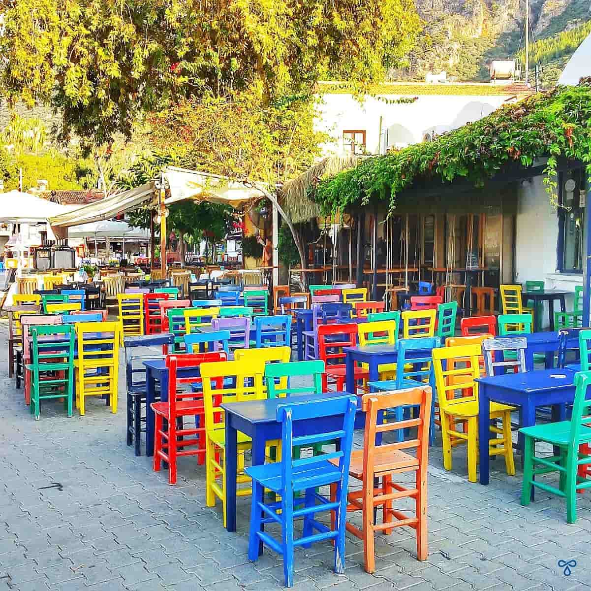Multi-coloured chairs and tables outside a vine-covered bar in Kaş.