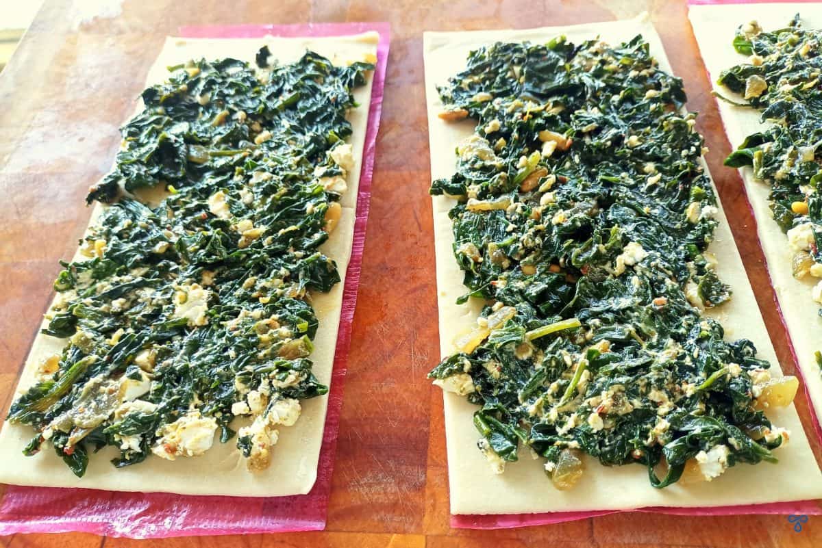 Twp rectangular puff pastry sheets with cooked spinach and cheese mixture spread over the top.