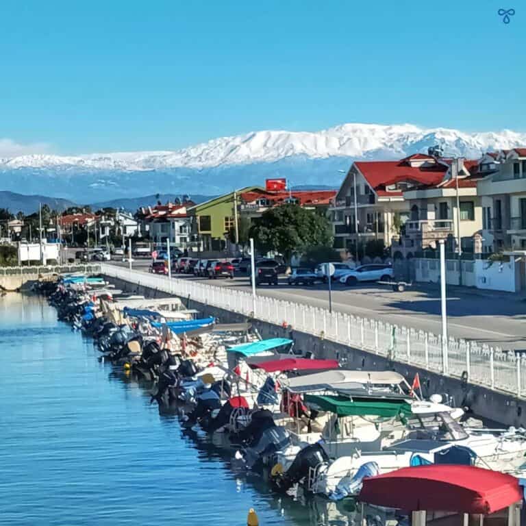 Motor boats moored up in Fethiye with snowy mountains in the background