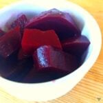 A close up of a white ramekin dish with chunks of pickled beetroot in it.