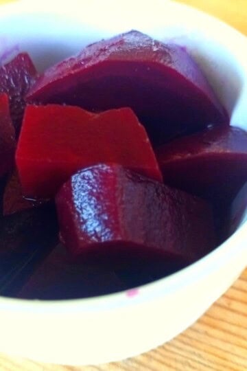 A close up of a white ramekin dish with chunks of pickled beetroot in it.