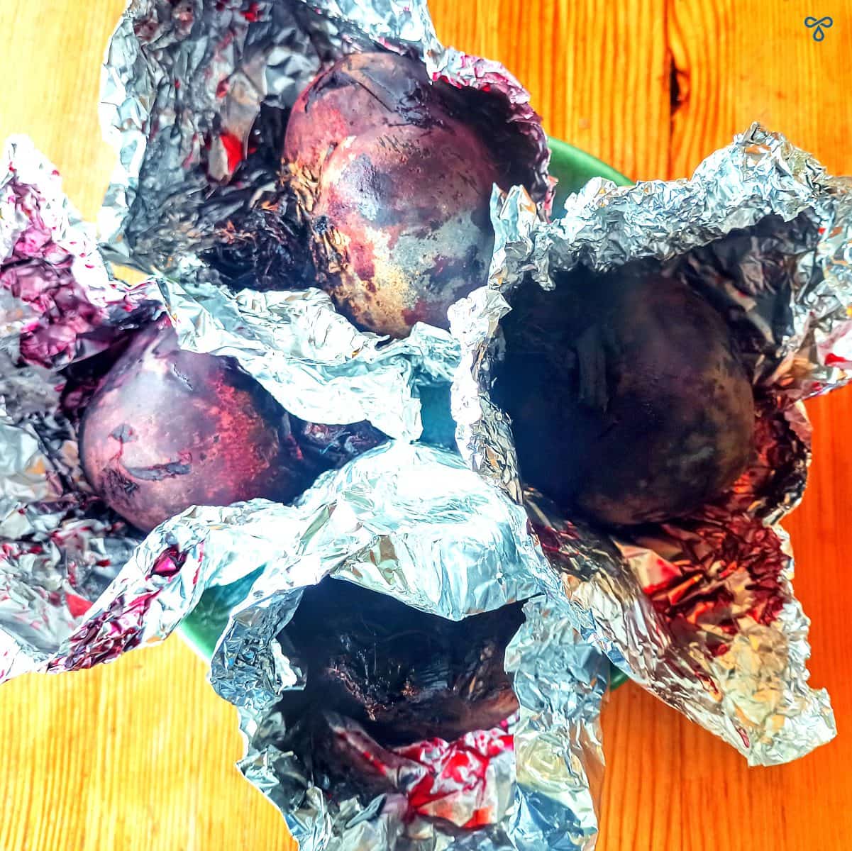 Four large beetroot wrapped in tinfoil with the tinfoil open at the top.