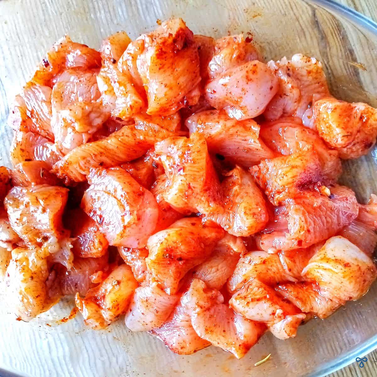 Bite-sized pieces of raw chicken breast in spices.