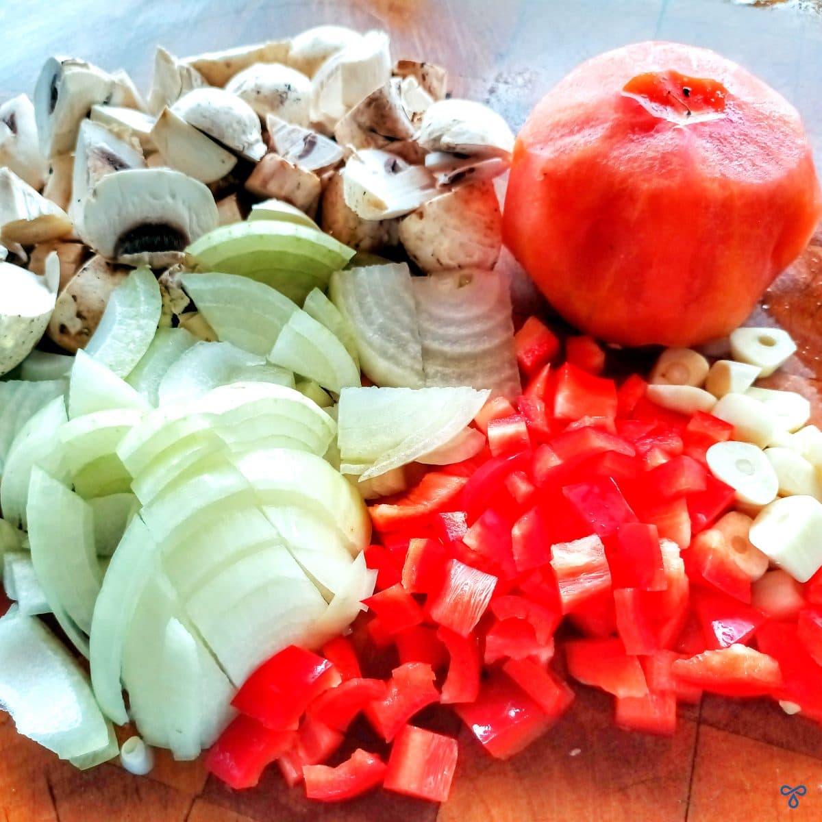 Chopped onion, mushroom, red pepper and garlic with one whole peeled tomato grouped together