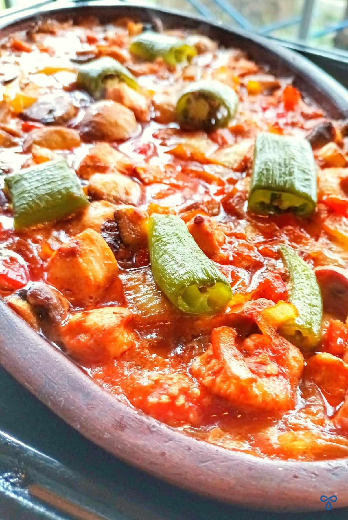 A green pepper-topped casserole in a shallow oval bowl.