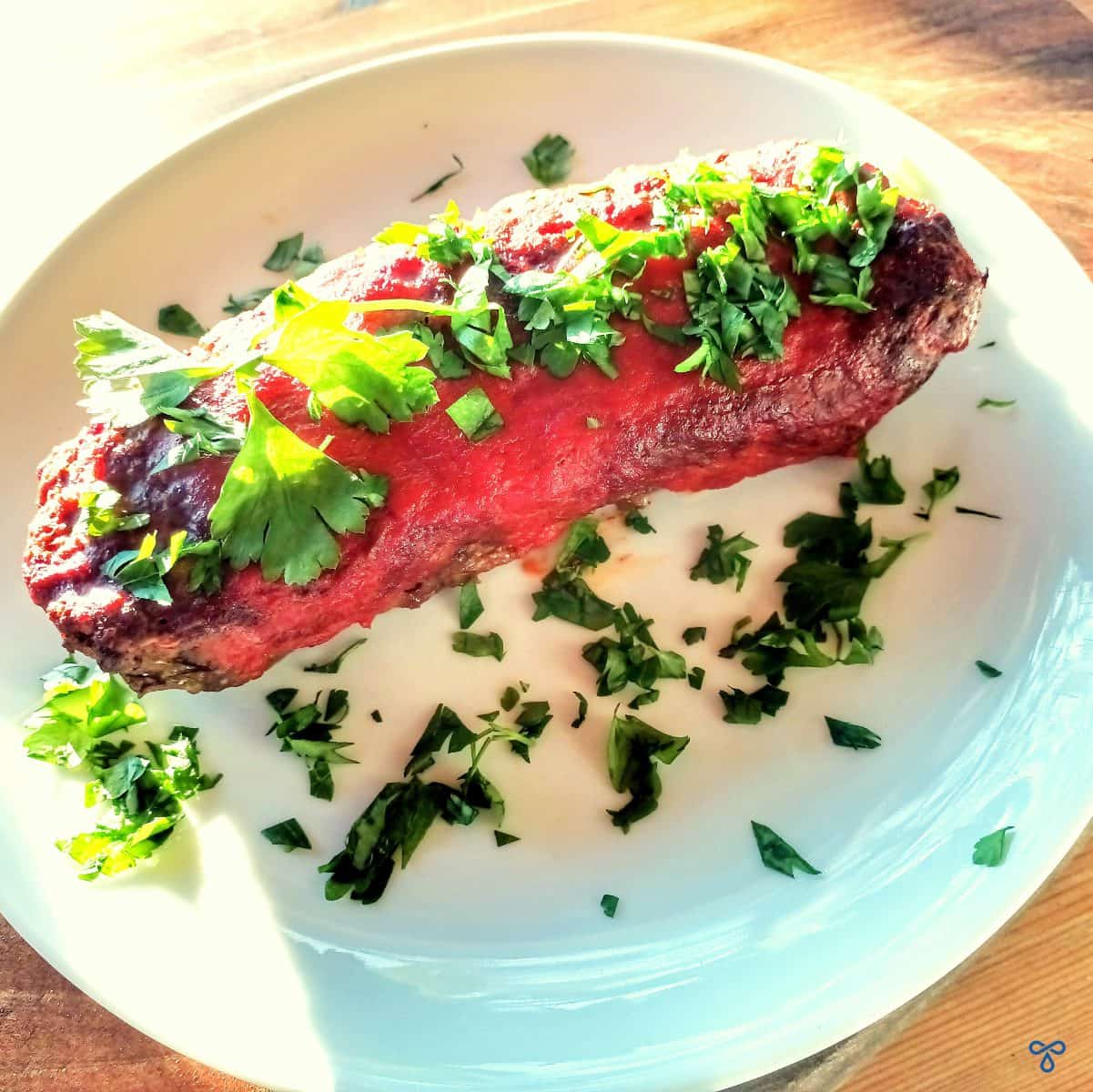 A whole meatloaf topped with fresh, chopped parsley.