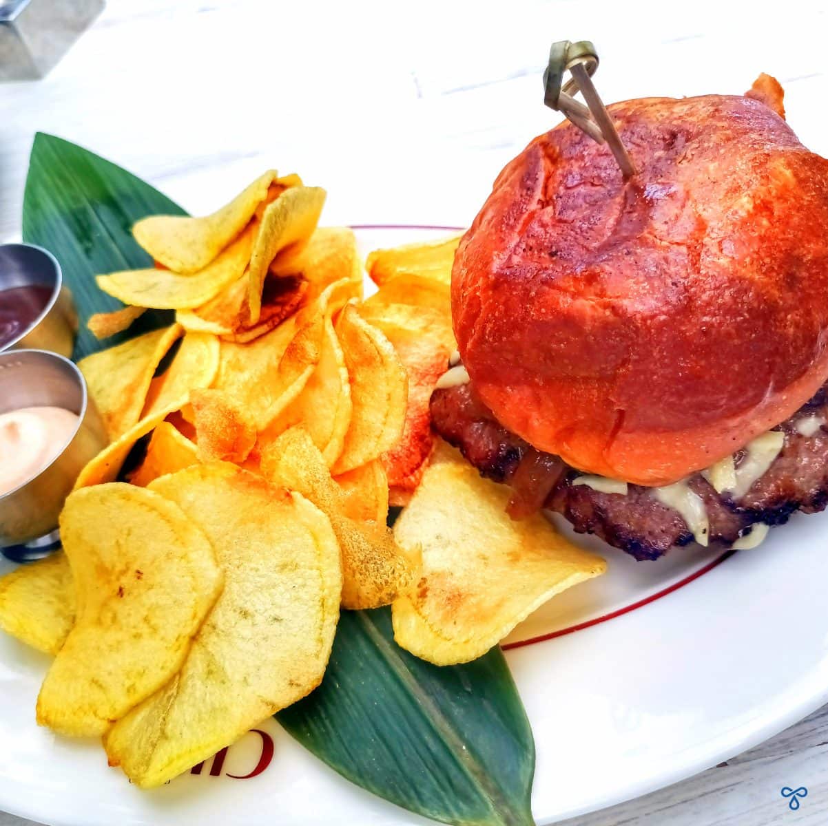 A photo of a cheeseburger taken from above. The burger is served with homemade thinly sliced deep fried potatoes.