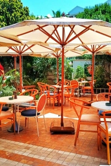 Scattered round tables and chairs shaded by large cream coloured parasols.