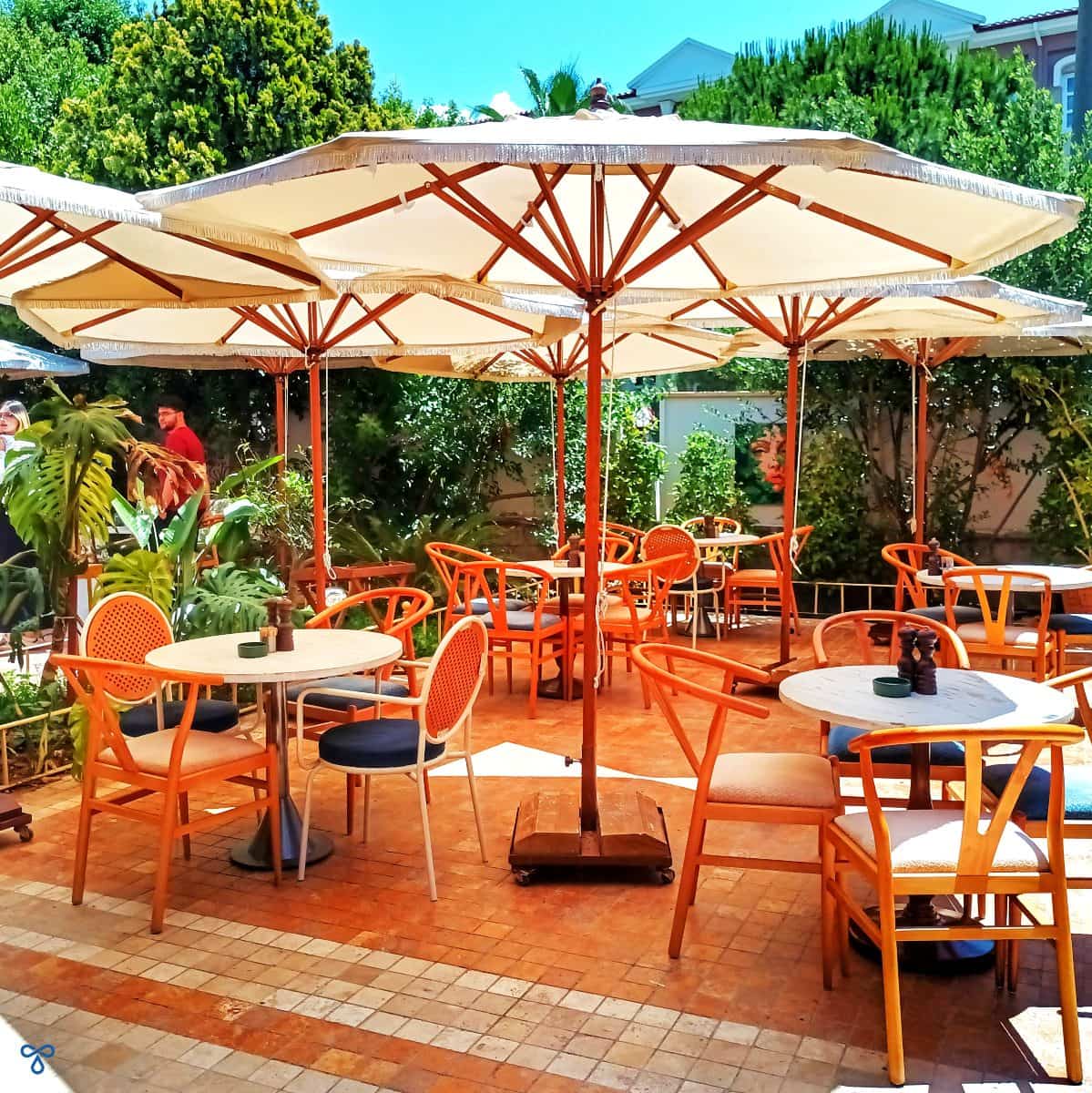 Scattered round tables and chairs shaded by large cream coloured parasols at Chez Community.