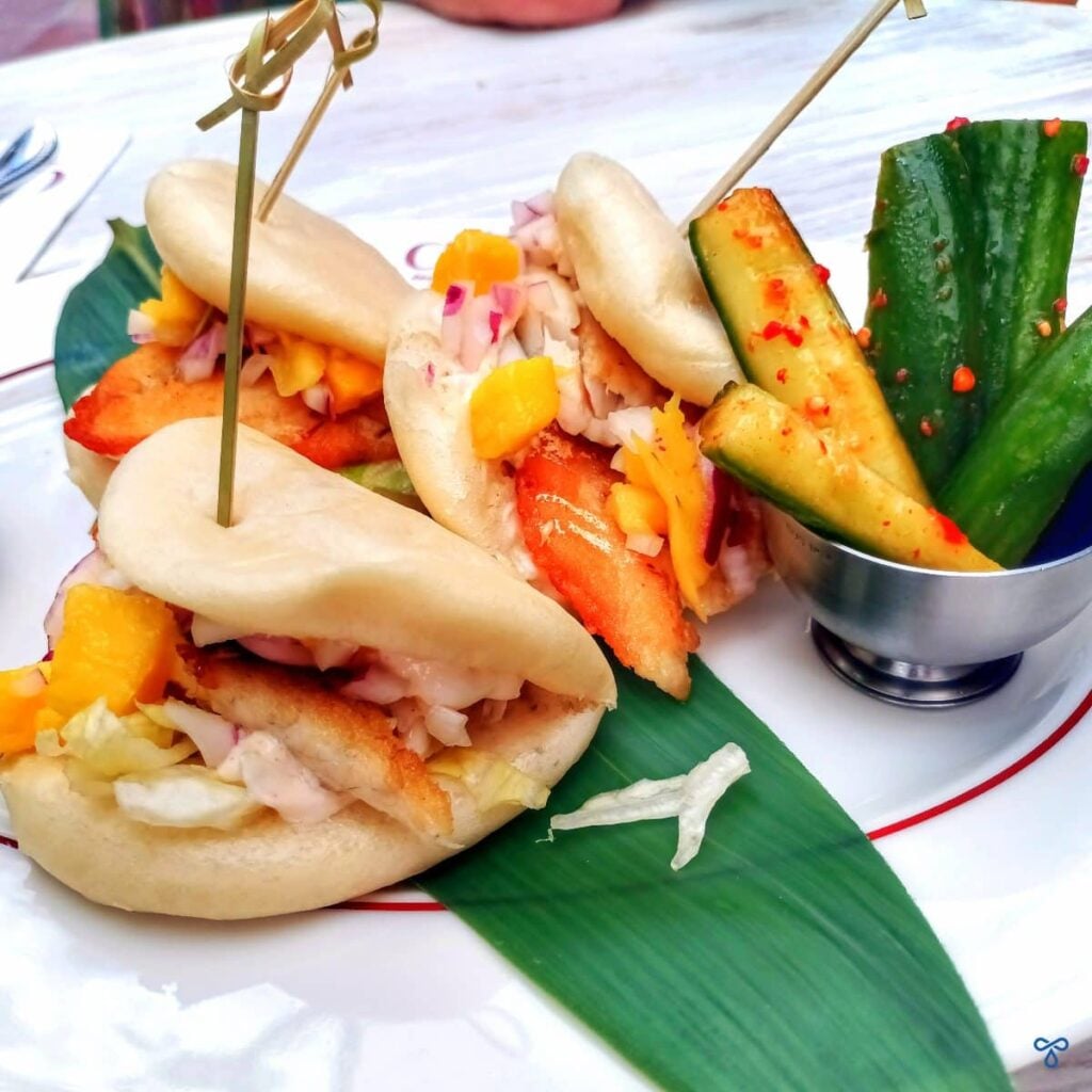 Chez Community bao buns filled with seabass served with a side of pickled cucumbers.