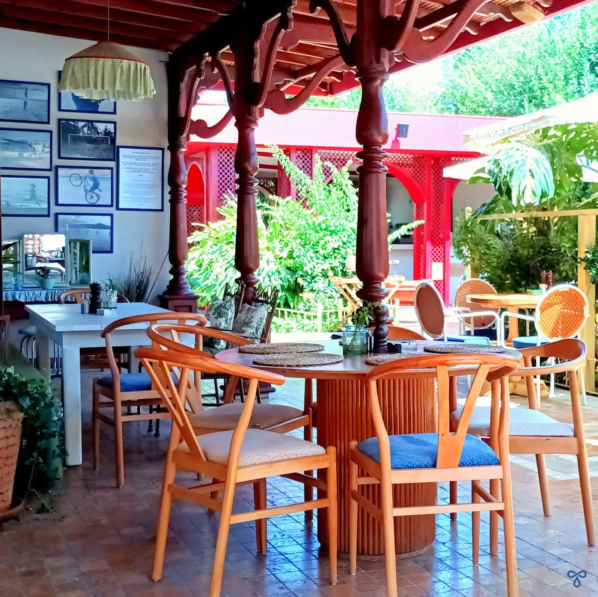 Restaurant setting with tables and chairs under a decorative wooden canopy.