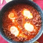 Four eggs poached in minced beef and juices. The photo is taken from above.