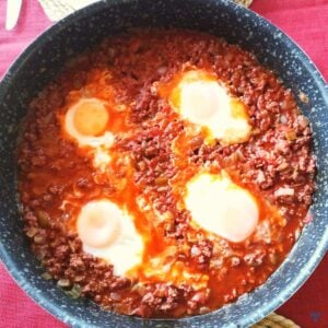 Four eggs poached in minced beef and juices. The photo is taken from above.