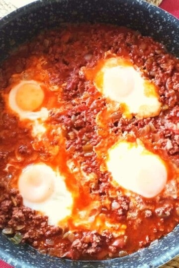 Four eggs poached in minced beef and juices. The photo is taken from above.