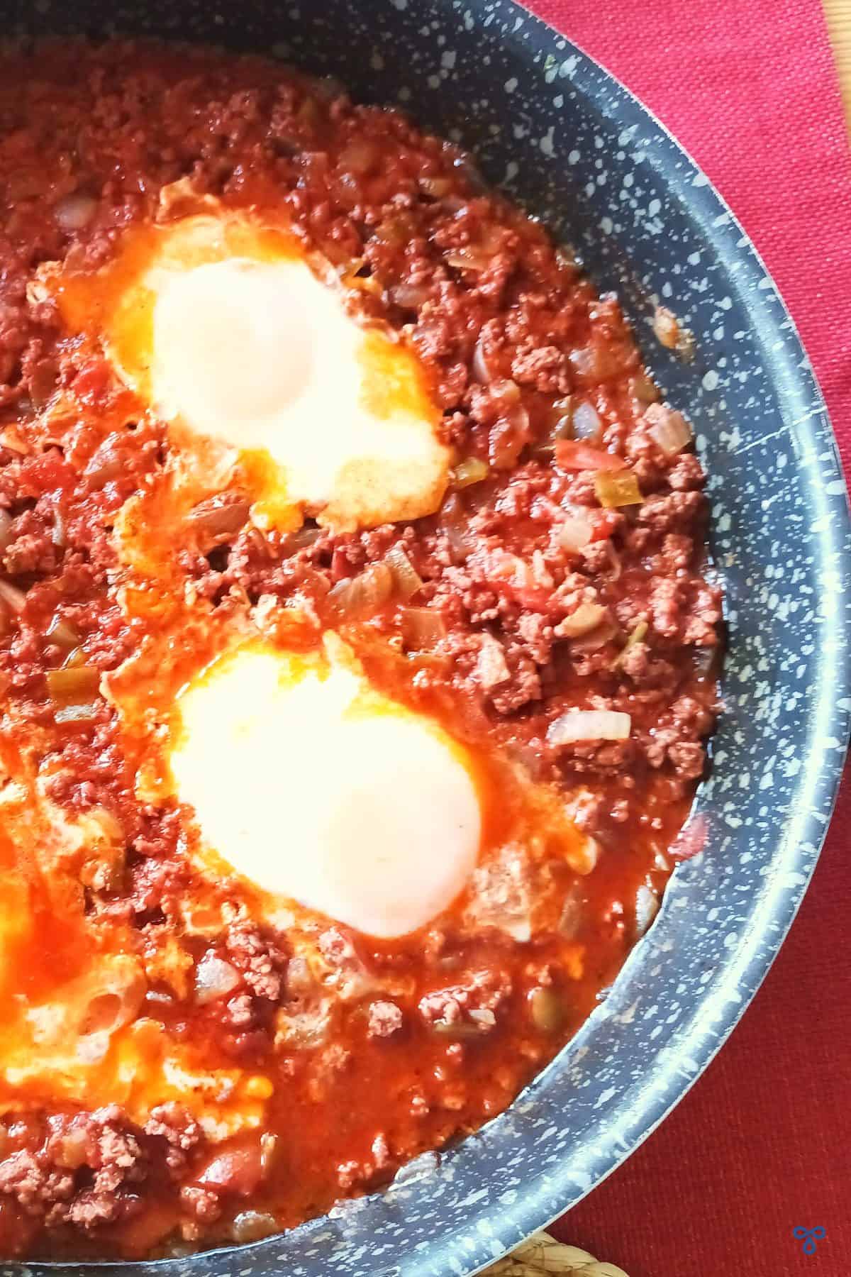 Turkish minced beef and eggs in the pan. The photo is in portrait mode and taken from above.