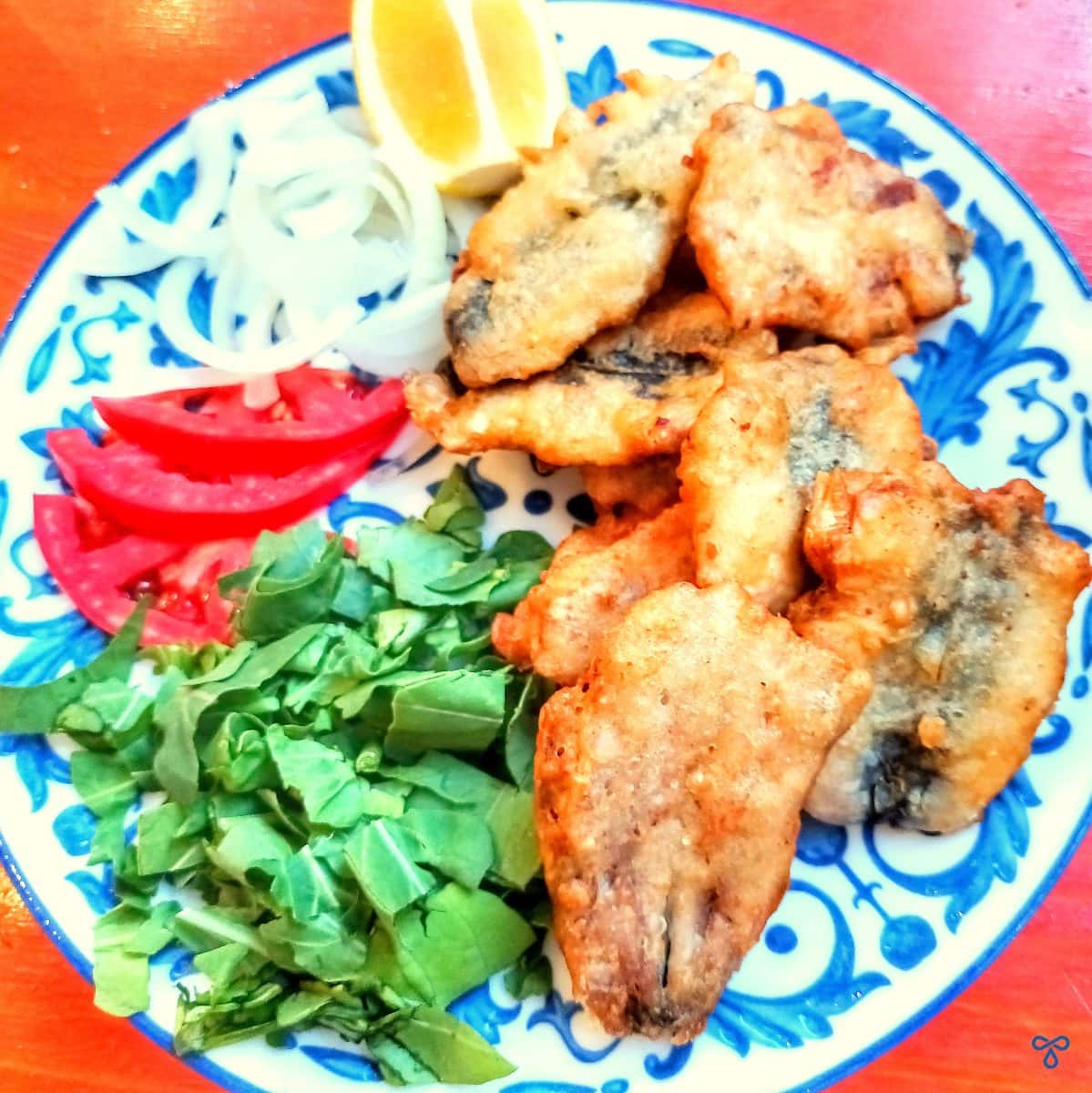 Butterflied deep fried battered sardines with a side of rocket, lemon, onion and tomato.