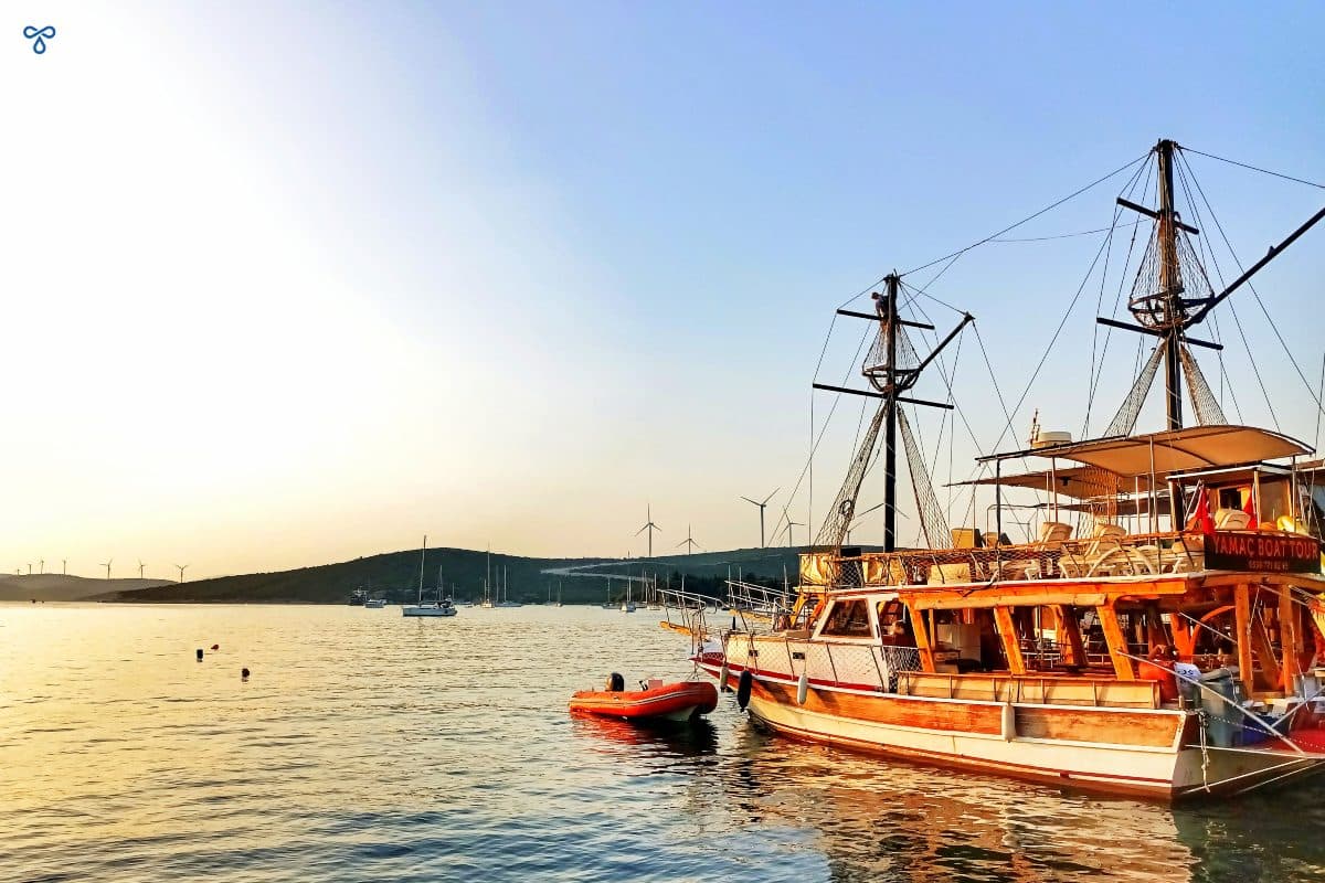 A wooden gulet boat anchored in the harbour as the sun is setting.