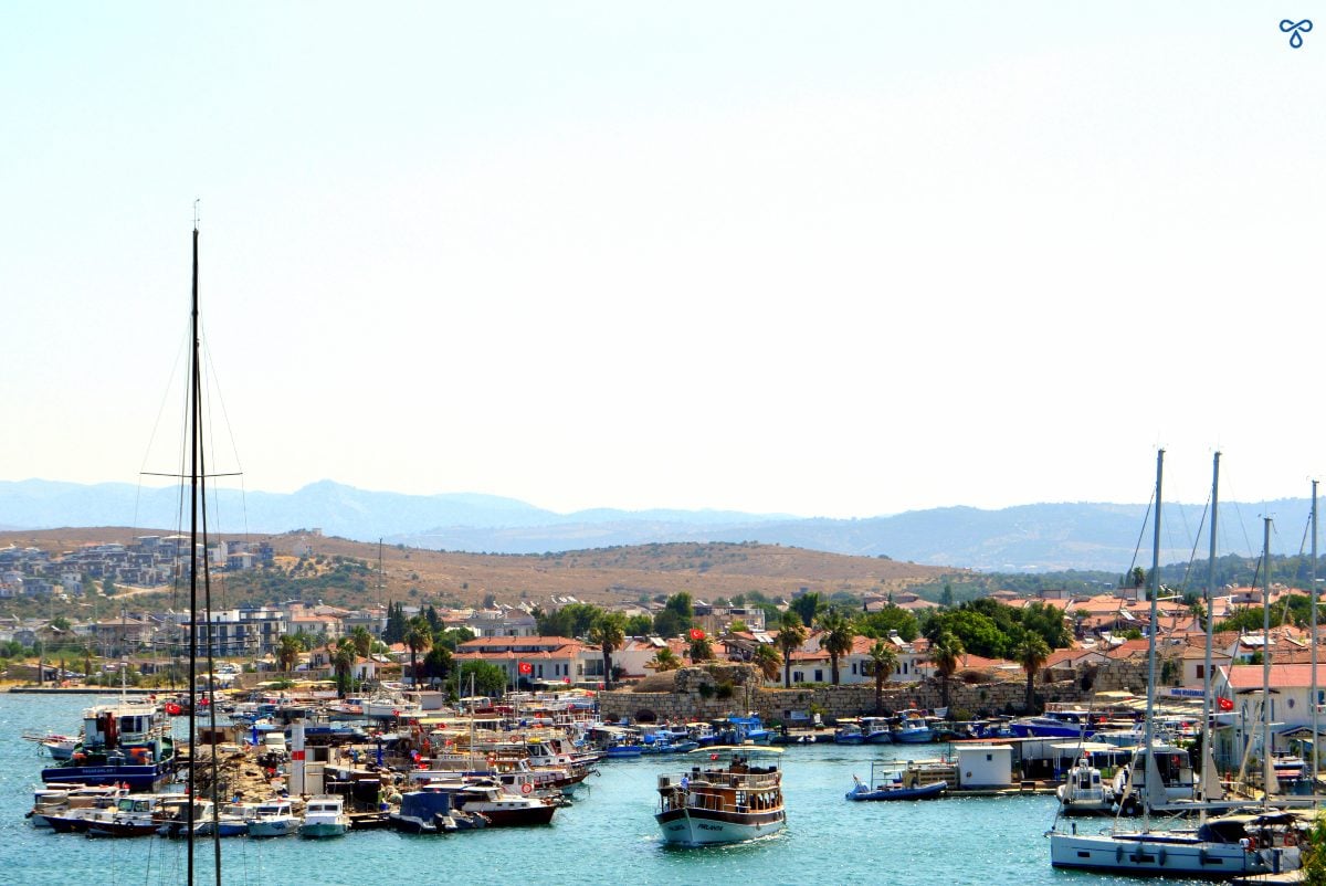 A boat leaving the small harbour of Sığacık, Seferihisar. The town and low lying hills are in the background.