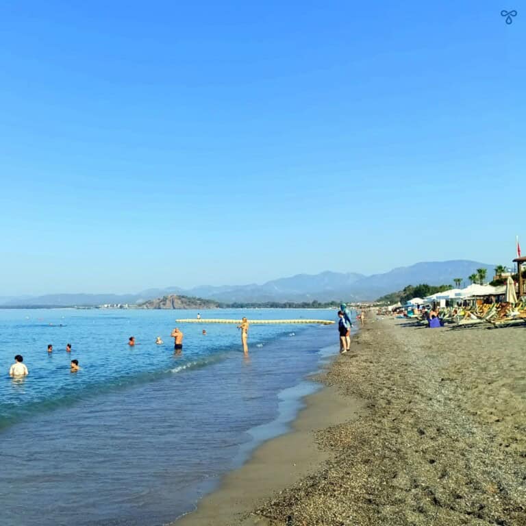 People swimming in a calm sea and a few sunbathing on the beach in Çalış.